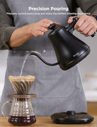 Person pouring water from a black kettle into a coffee dripper.